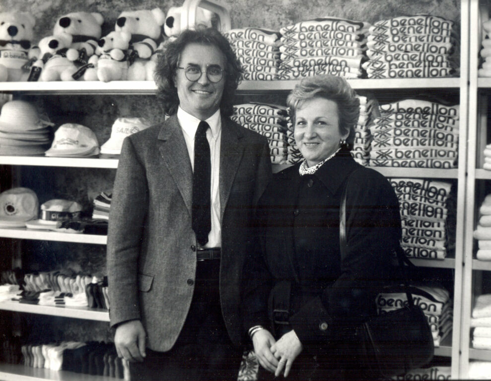 Man and woman standing in front of wall of clothing