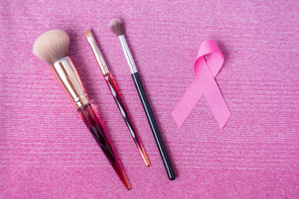 October Breast Cancer Awareness month, Pink Ribbon and cosmetic makeup brushes on pink shirt for supporting people living and illness. Healthcare, International Women day and World cancer day concept