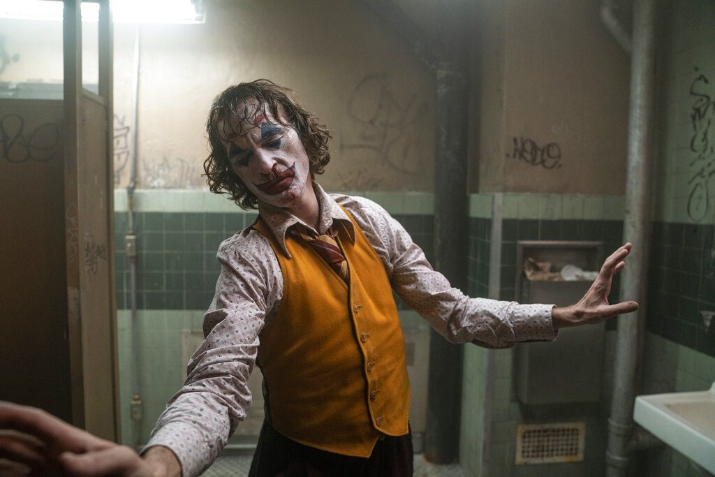 A man in clown makeup dances in a bathroom.