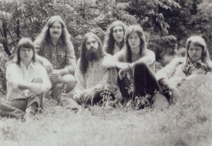 Six men sit in a field