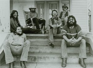 Six men lounge on a porch, smiling
